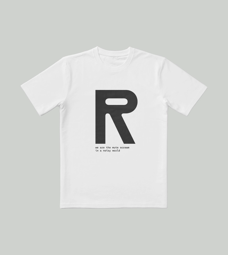 En hvid T-shirt med et stort sort bogstav R trykt midt på, og en lille tekst nedenunder, hvor der står: »Vi er det klare skrig i en støjende verden.« Baggrunden er lysegrå.